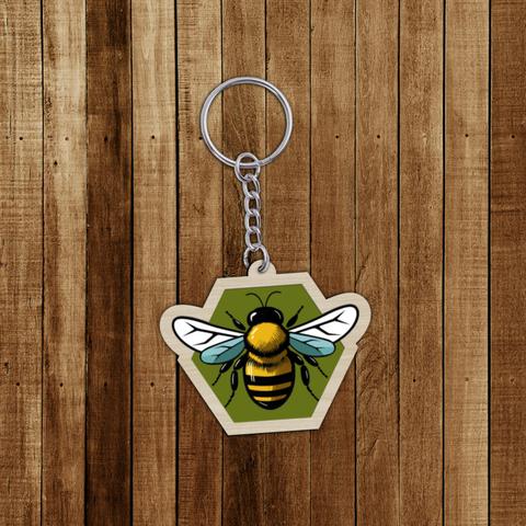 Porte-clés en bois décoré d'une abeille sur un fond hexagonal vert. A retrouver dans notre boutique en ligne : ernestine-etcie.fr