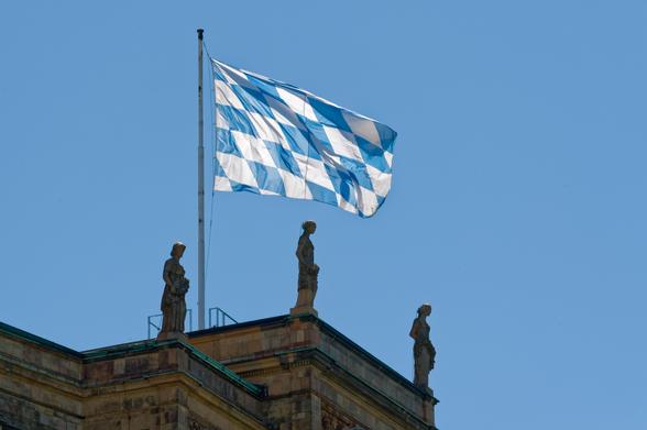 Das Bild zeigt drei Viktoria-Figuren auf dem Dach des Maximilianeums und die Bayerische Rautenflagge. | Foto: Rolf Poss