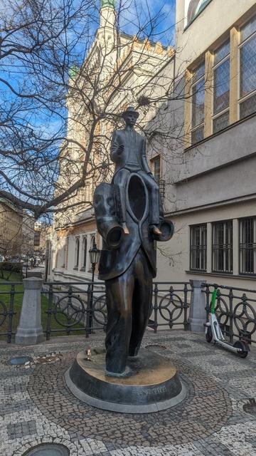 The Franz Kafka monument depicts, in bronze, a smaller man sitting on the shoulders of what should be a larger man, but he is missing and it's simply an empty suit in the shape of a man.