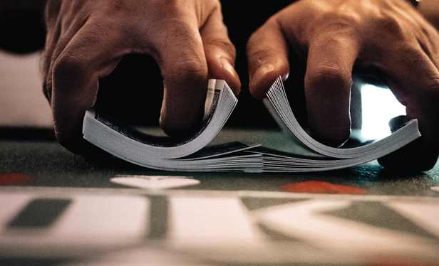 image of a person's hands shuffling a deck of cards on a poker table