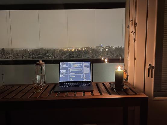 Candlelit MacBook on a bar table facing the window. Environment is snowy, cold, and dark.