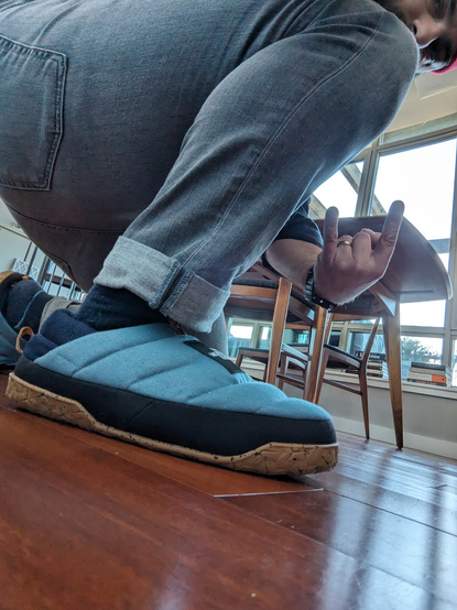 A selfie of me kneeling down showing off my new puffy north face slippers the upper is light blue and the lower is gum colored
