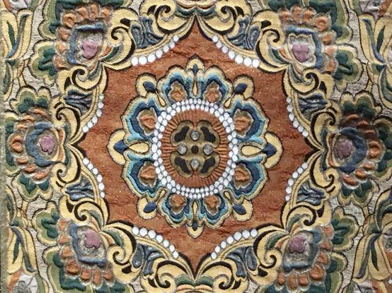 Décor à motifs symétriques et multicolores, entourant une fleur centrale.