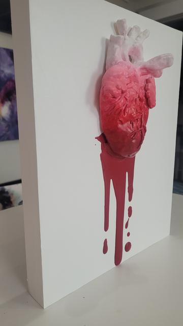 Photo at 45 degree angle of a 3 dimensional painting of an anatomical heart with blood red drops