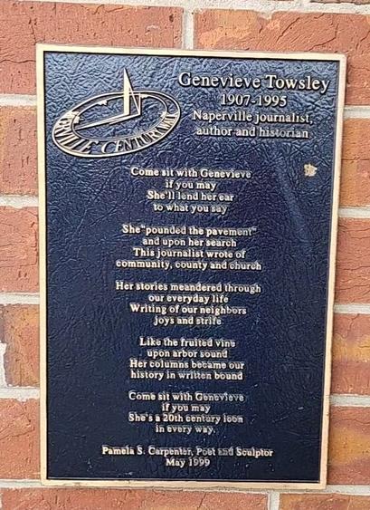 Image of a black plaque with gold letters, on a red brick wall. The plaque reads:

Genevieve Towsley 
1907-1995 
Naperville journalist, author, and historian

Come sit with Genevieve if you may
She'll lend her ear to what you say

She "pounded the pavement" and upon her search 
This journalist wrote of community, county, and church

Her stories meandered through our everyday life 
Writing of our neighbors' joys and strife

Like the fruited vine upon arbor sound
Her columns became our history in written bound

Come sit with Genevieve if you may 
She's a 20th century icon in every way.

Pamela S. Carpenter, Post and Sculptor
May 1999


[At the corner of Washington Street and Chicago Avenue, Naperville Illinois, January 2024]