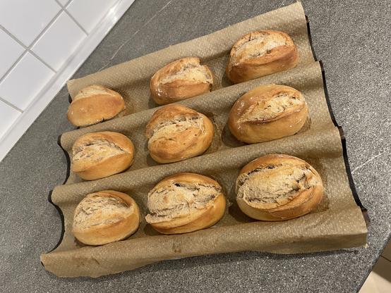 A batch of freshly baked bread rolls on parchment paper.