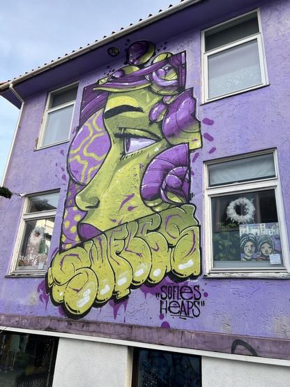 Big wall mural depicting ladys head in profile, done in purple and yellow.