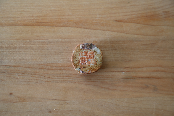 a circular trinket made out of ceramic with my family name (正) arranged in a logo as on my website. inside is an NFC sticker that links to my website
