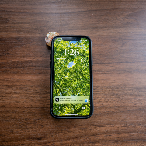 The name stamp from the first picture is shown under the top left corner of an iPhone. On the iPhone is a prompt to open "spencerchang.me" in Safari.