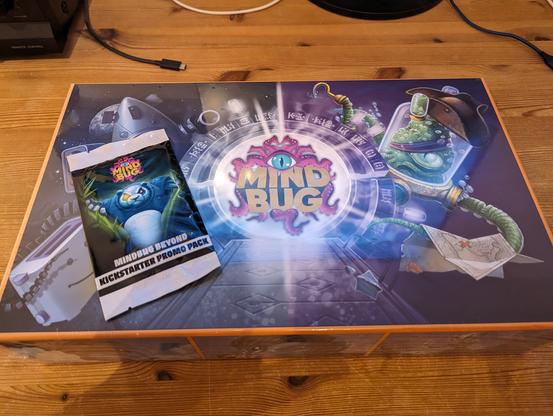 Mindbug game box with pack of promo cards on top