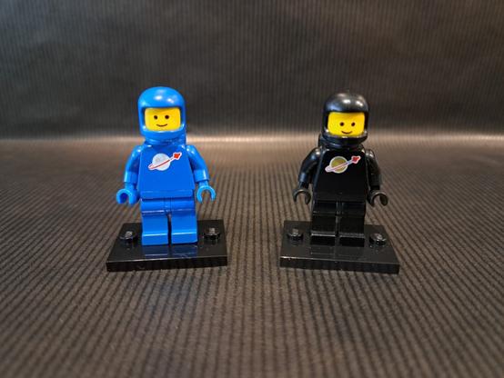 Deux figurines LEGO, du thème "Space". Une bleue et une noire. Elles sont côte à côte.