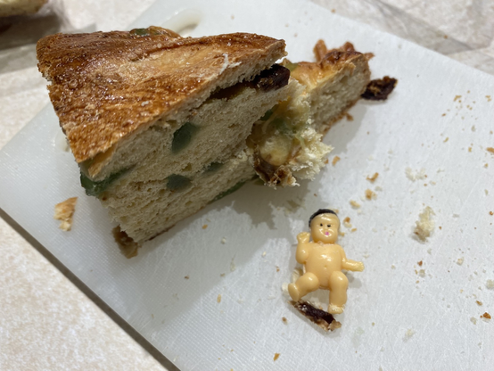Slice of three kings cake with the baby freed and next to it.