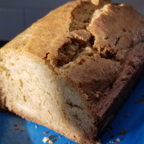 A delicious loaf of acorn squash bread with a slice cut out. The loaf has a beautifully browned outside & a golden fluffy inside.