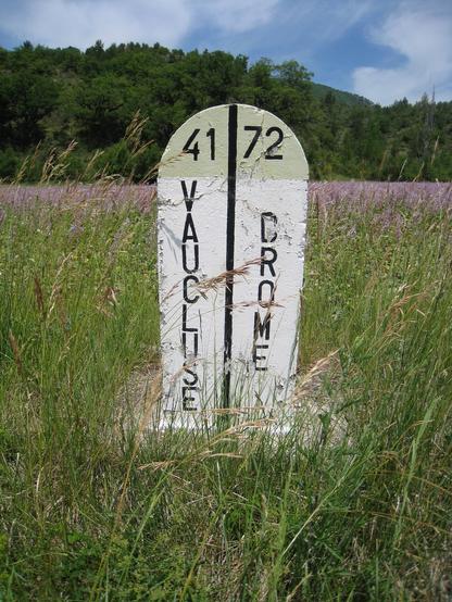 Dans un champ une borne marque les limites des départements du Vaucluse et de la Drôme
