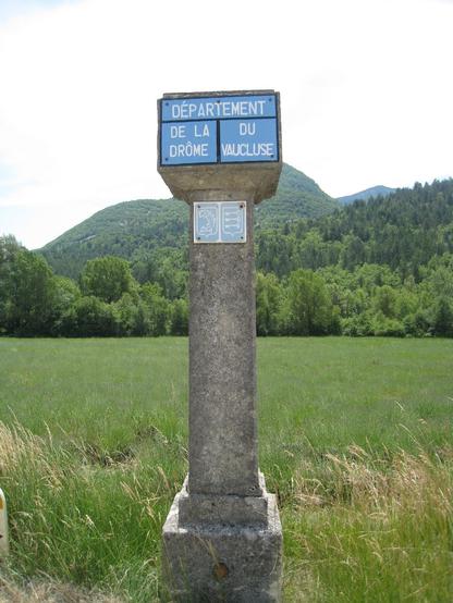 Devant un champ et une petite montagne, la limite des départements du Vaucluse et de la Drôme