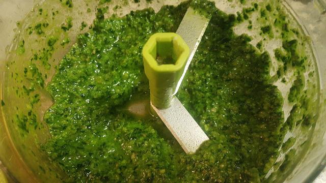 Recipiente de una picadora manual con la salsa de pesto recién hecha.