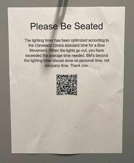A sheet of letter-sized printer paper taped to a grey wall. It reads:

Please Be Seated

The lighting timer has been optimized according to the Cleveland Clinics standard time for a Bow Movement. When the lights go out, you have exceeded the average time needed. BM's beyond the lighting timer should done on personal time, not company time. Thank you.

Beneath this is a QR code that decodes to:

https://health.clevelandclinic.org/how-long-should-it-take-you-to-have-a-bowel-movement/