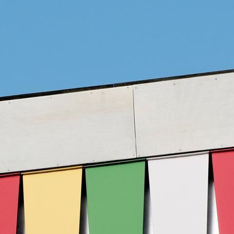 Edges of modern buildings featuring striking patterns of primary and secondary colored panels against the backdrop of a clear blue sky.