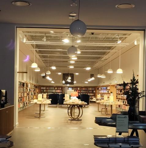 An inviting warm scene with cosy chairs, warm bright but not too bright lights and shelves and shelves full of books...