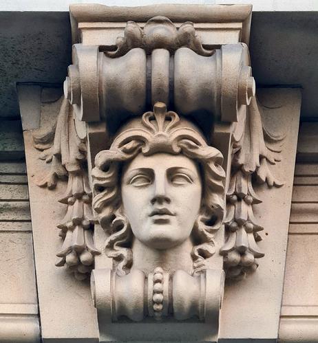 A sculpted female mask on a Grecian style keystone over the entrance to an Edwardian building.
