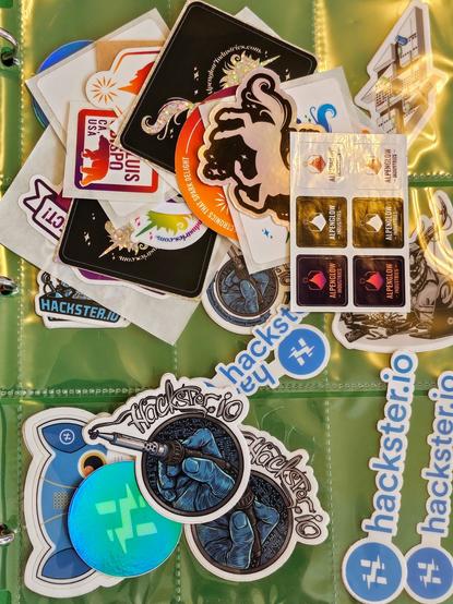 a jumbled pile of Hackster and Alpenglow stickers; not sure which is greater in quantity yet...?!