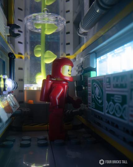 A classic LEGO space minifig in a botany space lab looking at an electronics panel. The lab is narrow with a tall cylinder in the back that has a plant inside.