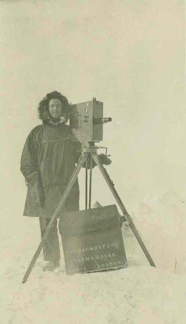 An old photo of a man with a camera on a tripod.