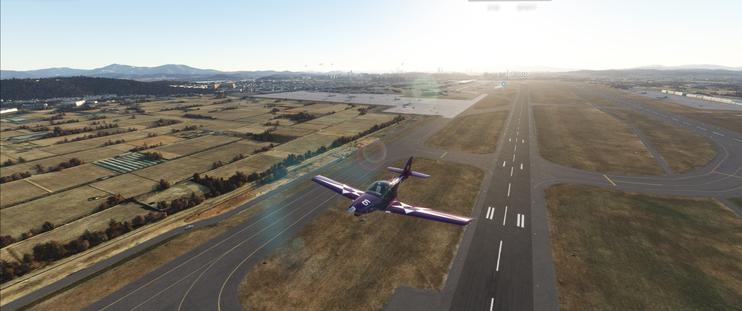 A JMB VL3 taking off from Seoul-Gimpo, flying north towards the camera with Seoul behind it.