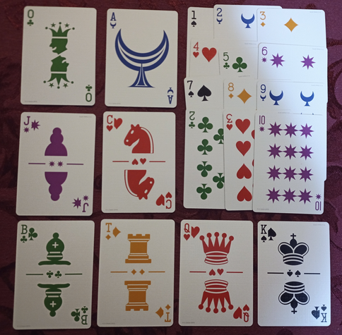 Twenty playing cards in a grid, showing the cards of a K6T+Dozenal deck. Cards one through dozen overlapped top right, with eight other cards displayed nearby. Cards are in six colors (red hearts, orange diamonds, black spades, green clubs, purple stars, blue moons. The court cards are from chess: Pawn/Jack, Knight/Cavalier, Bishop, Tower, Queen, King. Also shown are a Zero/Joker and an Ace.