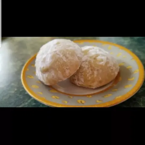 Two finished ma'amoul filled with walnuts on a little decorative plate.