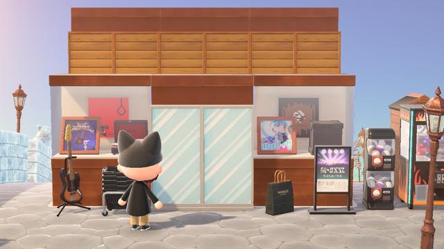 Animal Crossing: New Horizons screenshot. A light skinned villager with a long black coat and a black cat ear hat is standing in front of a faux, dark wooden building intended to look like a record store. The left window has a custom design displayed that looks like the cover of Goldfinger's Hang Up (Design ID MO-3Y2T-F237-2CKQ) with K.K. Metal on display in front of it and a black record player. The right window display has a custom design displayed that looks like the cover of Dreamcatcher's Apocalypse: Save Us (Design ID MO-JS9L-98KR-C018) with K.K. Robot Synth in the window along with a black box of records. On the left side of the simple panels intended to look like sliding glass doors is a bass guitar and a stack of black store baskets. On the right side of the simple panel doors is a black store bag and a sign that shows a concert going on. To the right of the faux building is a black capsule machine and a black, flame covered crane game.