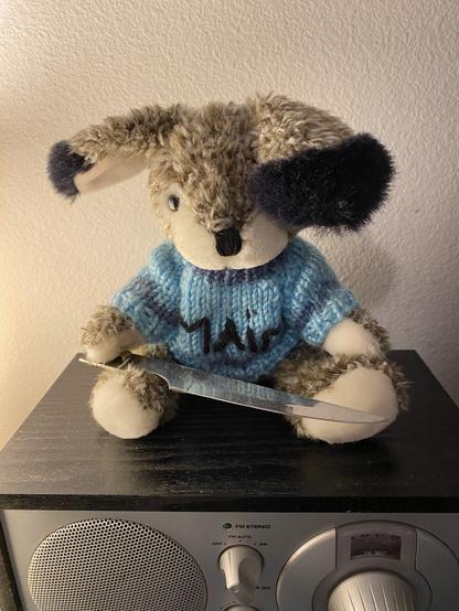 My plush bunny wearing a sweater with the word "MAIM" embroidered onto the front. She carries a metal knife longer than her torso in her right paw.