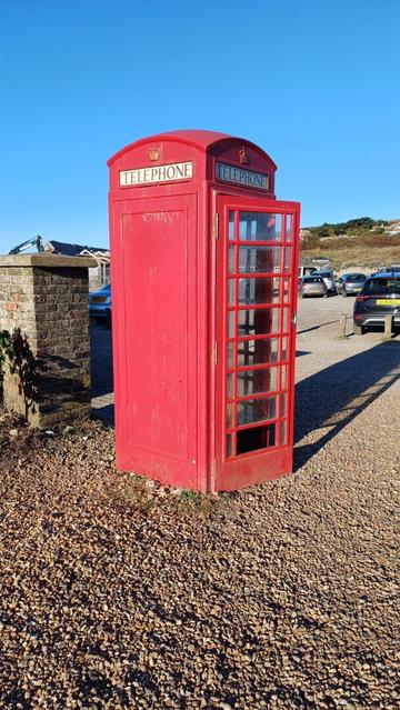 Iconic and classic British Red telephone box with glass framed door broken and open