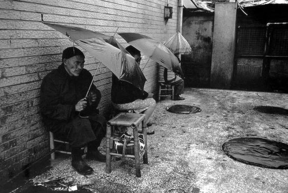 A black-and-white photograph entitled "zero focus" by Chang Chao-Tang, at the Massage Corner, in Taipei, Taiwan in 1984.

Persons are sitting on stools, holding umbrellas to protect from the rain.