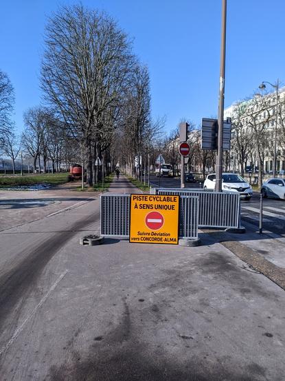 Une piste cyclable barrée d'un panneau temporaire qui annonce : « piste cyclable à sens unique. Suivre déviation vers Concorde - Alma »