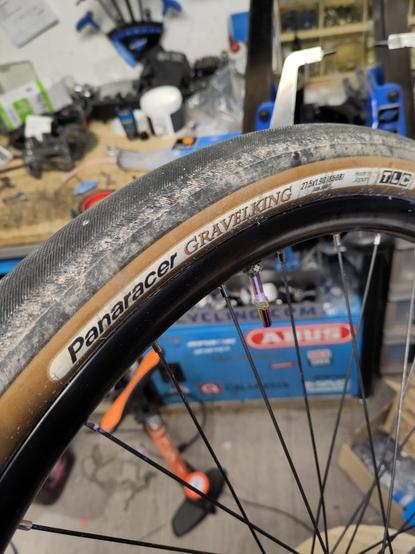 Pneu Panaracer Gravelking à flancs beige monté sur une jante noire pas forcément compatible avec une valve MucOff irisée
