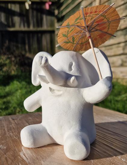 Clay model of the mastodon elephant mascot sitting down and holding a cocktail umbrella