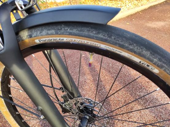 Détail de la roue avant avec le pneu à flancs beige et la valve irisée