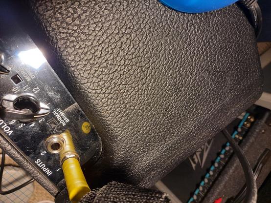 Top of Fender Hot Rod Deville amp showing black tolex and silver faceplate with control knobs and inputs. New  Switchcraft input jacks are installed. Yellow cable is in input 1. Small Peavey amp can be seen in the background.