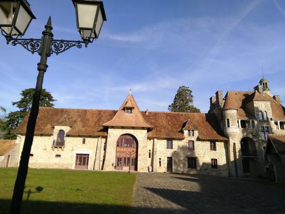 Photo au format paysage de la Médiathèque du château des Dames au Châtelet-en-Brie en Seine-et-Marne. En premier plan un réverbère. La médiathèque est dans une ferme fortifiée du 14e siècle : le château des Dames. Il tient son nom des religieuses de l'abbaye Saint-Louis de Poissy, détentrices de la seigneurie des terres du Châtelet du 14e siècle à la Révolution.