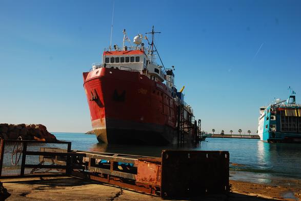 das rettungsschiff "sea-eye4" wird gerade auf schlitten aus dem wasser gezogen, an land im vordergrund liegt ein stahlarm, mit denen schiffe gesichert werden