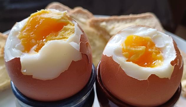 Two boiled eggs in egg cups with medium bright yellow yolks