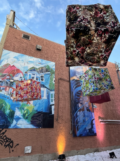 Chinese lanterns made out of brightly coloured fabric, hanging against the backdrop off a colourful mural depicting heritage homes in the area.