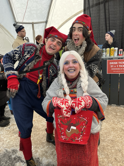 Three festival performers, two younger men and an older woman, dressed in colourful knitwear and makeup to make them look like Scandinavian gnomes