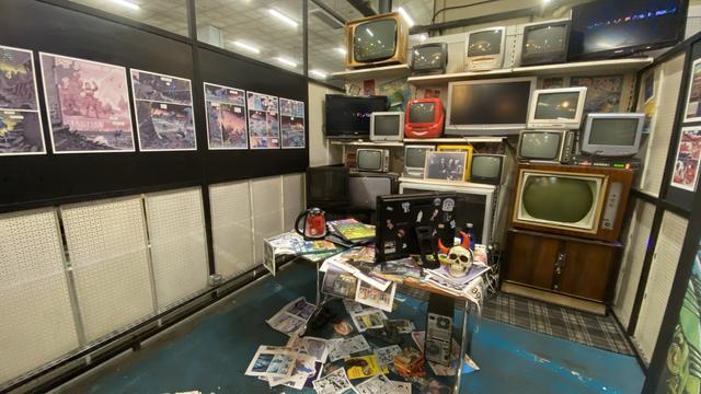 Réplique du bureau commun de Jerry Frissen, rédacteur en chef du magazine, et de Jean-Pierre Dionnet. Deux murs latéraux sont recouverts de planches du magazine, celui du fond est caché sous les vieux écrans cathodiques de toutes sortes, le bureau lui même est enseveli sous les objets et les tirages de planches. Enfin, le sol est jonchés de tirages repartis de manière chaotique.