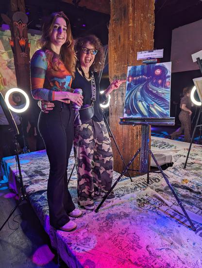My friend Denyse with Emily, the Canadian winner of last week's Art Battle San Francisco, standing by Emily's winning, second-round painting of a freeway interchange