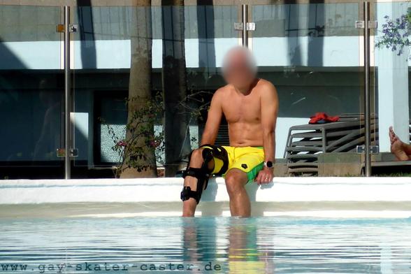 shirtless man sitting at the pool with a knee brace on