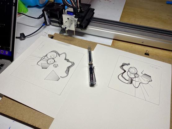 Both drawings next to pen for scale. Pen plotter behind.