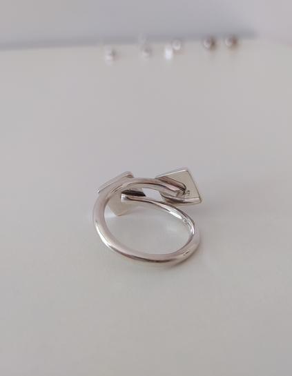 An open silver ring with two green square stones, each one in the other end. This is its inner side