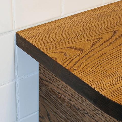 A close up of the corner of a white oak kitchen bar.